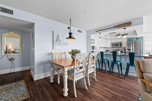 dining space with a raised ceiling, a textured ceiling, ceiling fan, and dark hardwood / wood-style floors