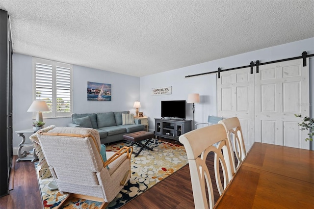 living room featuring dark hardwood / wood-style flooring, a barn door, and a textured ceiling