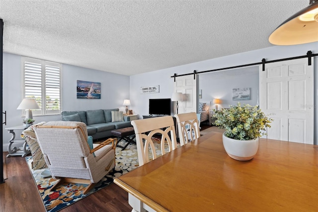 living room featuring a textured ceiling, a barn door, and hardwood / wood-style flooring