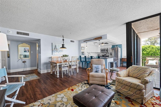 living room with a textured ceiling, ceiling fan, and dark hardwood / wood-style flooring