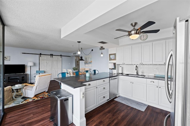 kitchen featuring appliances with stainless steel finishes, sink, kitchen peninsula, dark wood-type flooring, and ceiling fan