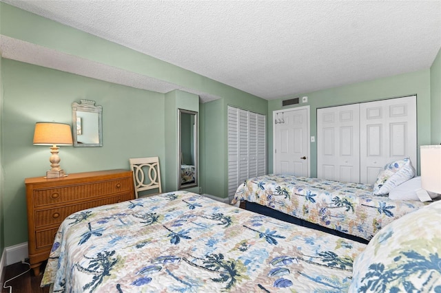 bedroom featuring a textured ceiling, dark wood-type flooring, and two closets