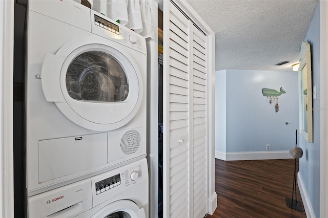 washroom featuring stacked washer / dryer, a textured ceiling, and dark hardwood / wood-style floors