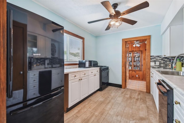 3108 58th St S, Gulfport, FL 33707 - kitchen with tasteful backsplash, white cabinetry, black appliances, ceiling fan, and a sink