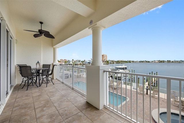 balcony with ceiling fan, a fenced in pool, and a water view