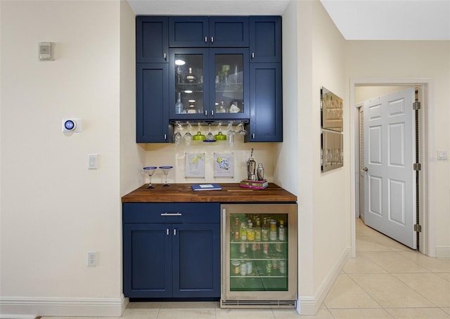 bar with butcher block counters, blue cabinetry, light tile patterned floors, and beverage cooler