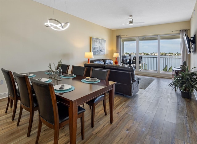 dining area with ceiling fan with notable chandelier and dark hardwood / wood-style floors