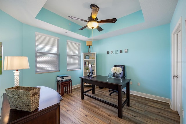 office area featuring ceiling fan, a tray ceiling, and hardwood / wood-style floors