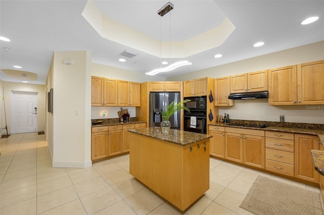 kitchen featuring dark stone counters, a center island, a raised ceiling, hanging light fixtures, and black appliances