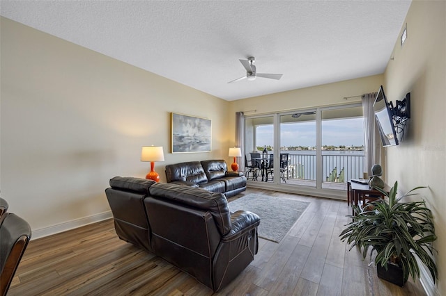 living room with ceiling fan, a textured ceiling, and wood-type flooring