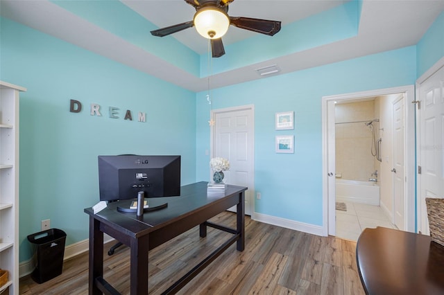 office with ceiling fan, hardwood / wood-style flooring, and a tray ceiling