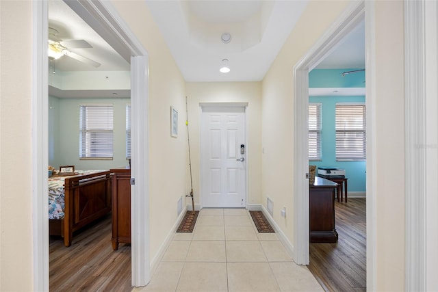 entrance foyer featuring ceiling fan, light hardwood / wood-style floors, a healthy amount of sunlight, and a tray ceiling