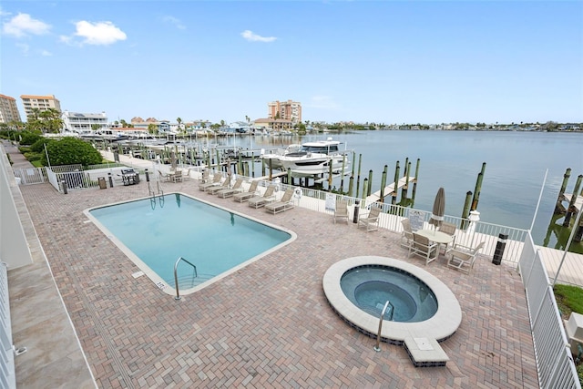 view of swimming pool with a hot tub, a water view, a patio, and a dock