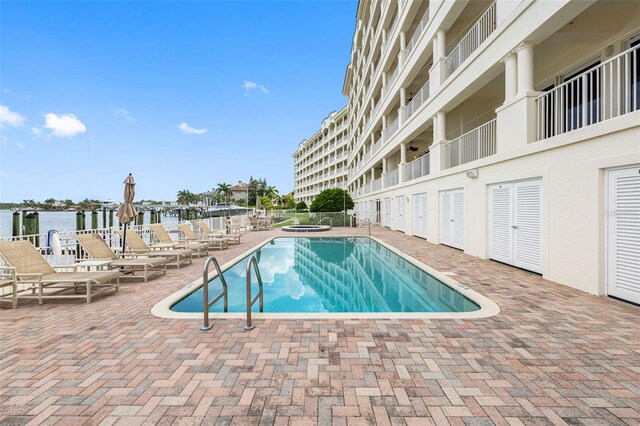 view of swimming pool with a patio and a water view