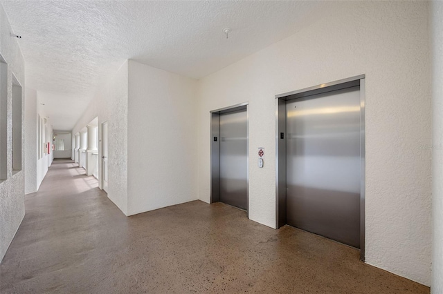 corridor with a textured ceiling and elevator