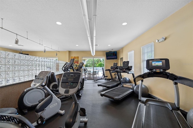 gym featuring track lighting and a textured ceiling