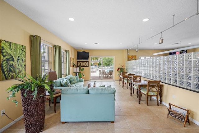 living room with a textured ceiling, light tile patterned flooring, and track lighting