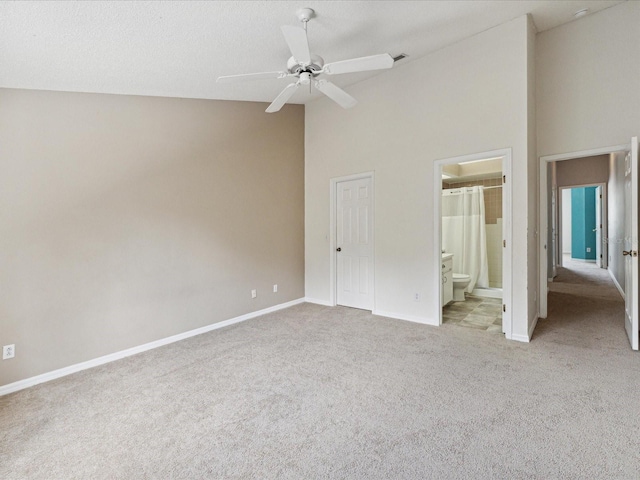 unfurnished bedroom with high vaulted ceiling, ensuite bath, a closet, ceiling fan, and light colored carpet