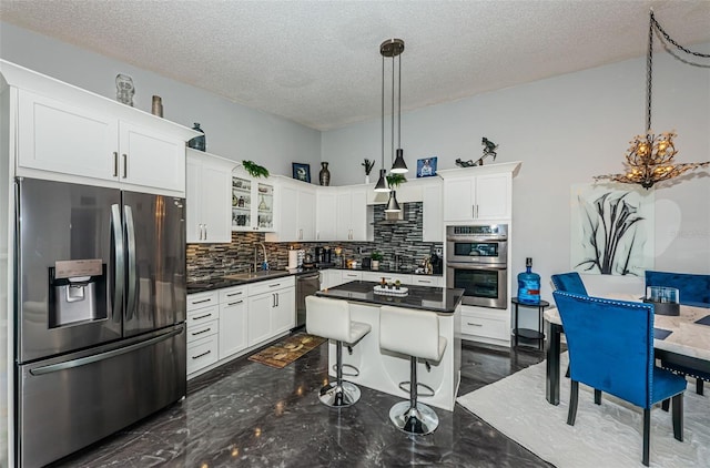 kitchen featuring dark hardwood / wood-style floors, pendant lighting, tasteful backsplash, white cabinetry, and stainless steel appliances