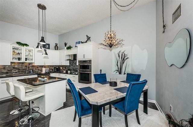 interior space with double oven, a towering ceiling, hanging light fixtures, and decorative backsplash