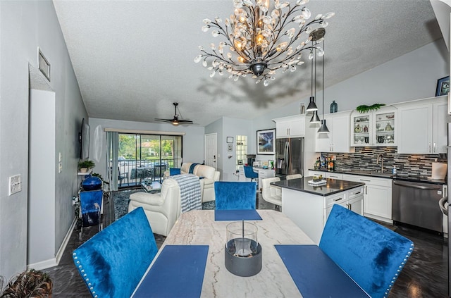 dining space featuring vaulted ceiling, a textured ceiling, and ceiling fan with notable chandelier