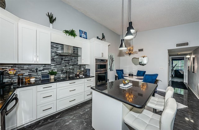 kitchen with wall chimney exhaust hood, tasteful backsplash, black gas stovetop, double oven, and white cabinets