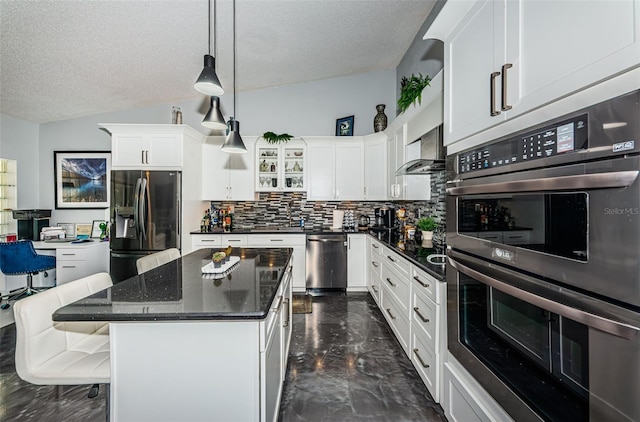 kitchen featuring decorative backsplash, white cabinets, a center island, lofted ceiling, and stainless steel appliances