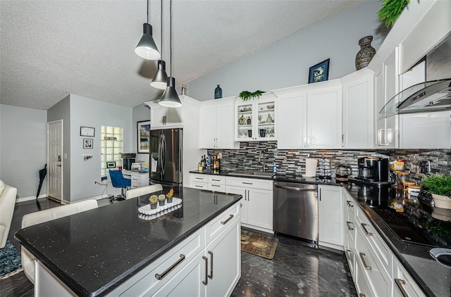 kitchen featuring decorative backsplash, a kitchen island, white cabinetry, appliances with stainless steel finishes, and sink