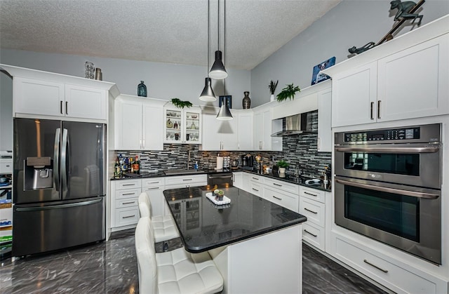 kitchen with decorative backsplash, a kitchen island, white cabinetry, a textured ceiling, and stainless steel appliances