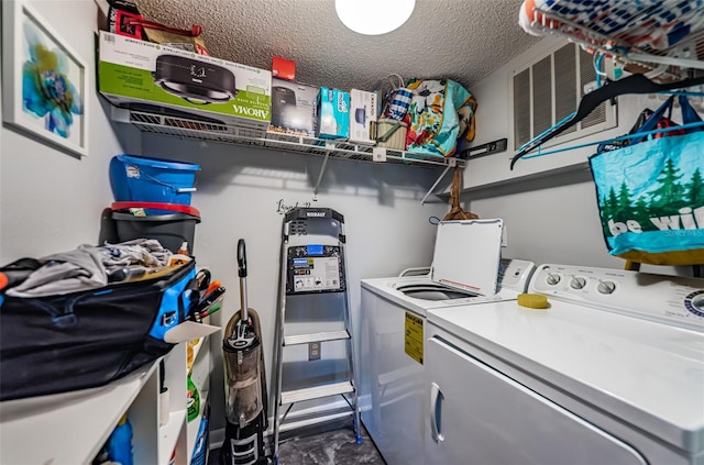 clothes washing area with washing machine and dryer and a textured ceiling