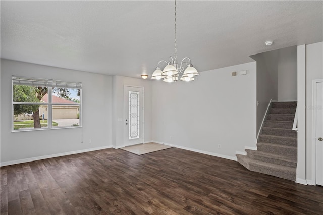 unfurnished room with dark hardwood / wood-style flooring, a notable chandelier, and a textured ceiling