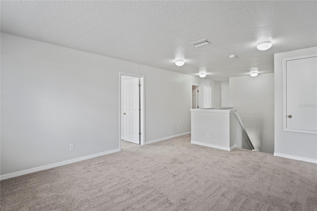 unfurnished room featuring a textured ceiling and light carpet