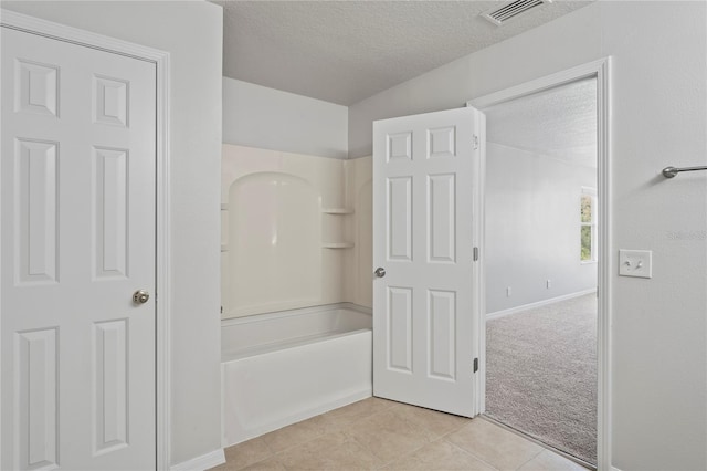 bathroom featuring a textured ceiling, tile patterned floors, and washtub / shower combination