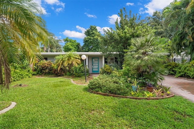 view of front of home featuring decorative driveway, fence, and a front lawn