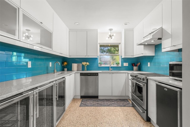 kitchen with stainless steel appliances, a chandelier, white cabinetry, tasteful backsplash, and sink