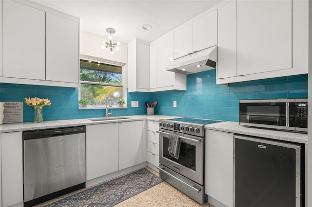 kitchen with decorative backsplash, white cabinets, appliances with stainless steel finishes, sink, and an inviting chandelier