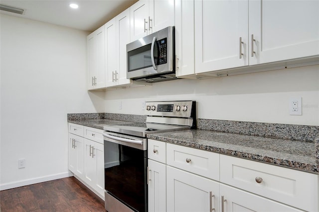 kitchen with white cabinets, dark stone countertops, dark wood-type flooring, and appliances with stainless steel finishes