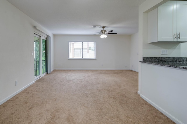 unfurnished living room featuring light colored carpet and ceiling fan