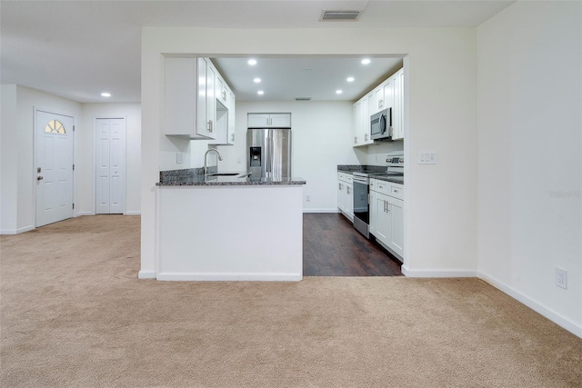 kitchen featuring sink, stainless steel appliances, dark colored carpet, dark stone countertops, and white cabinets