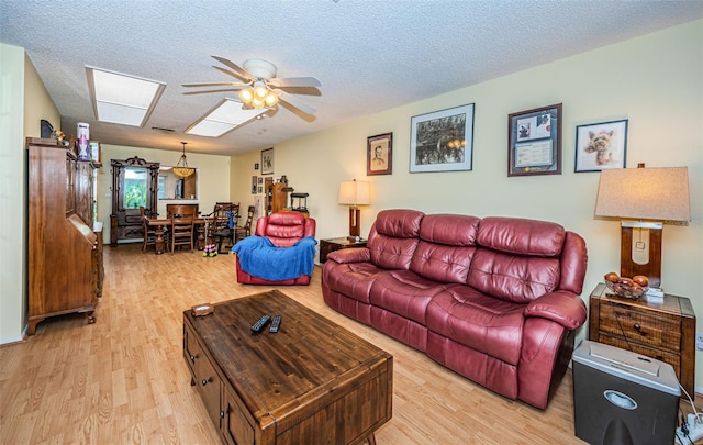 living room featuring ceiling fan, light wood-type flooring, and a textured ceiling