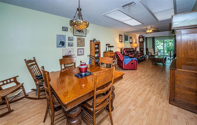 dining space with a textured ceiling, ceiling fan, and light wood-type flooring