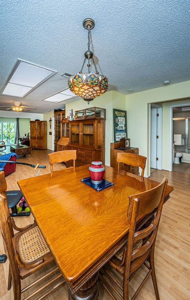 dining space featuring a textured ceiling, ceiling fan, and light wood-type flooring