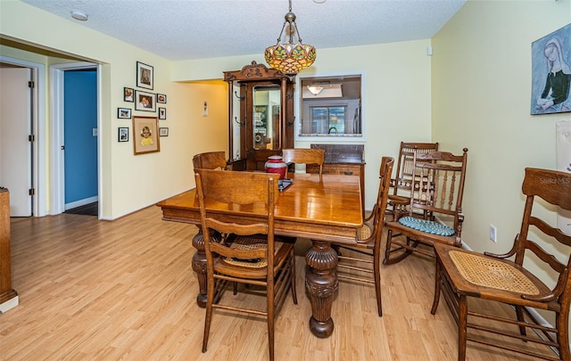 dining area with light hardwood / wood-style flooring and a textured ceiling