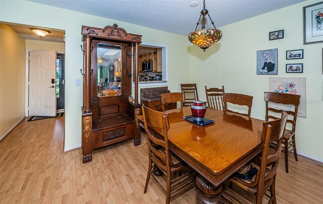 dining space featuring light wood-type flooring and a textured ceiling