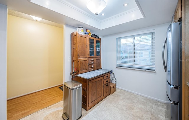 kitchen with a raised ceiling, stainless steel fridge, crown molding, and light tile patterned floors