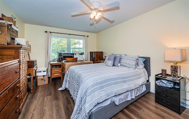 bedroom with ceiling fan, dark wood-type flooring, and a textured ceiling