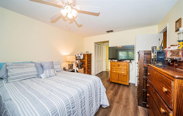 bedroom with a textured ceiling, ceiling fan, and dark hardwood / wood-style flooring