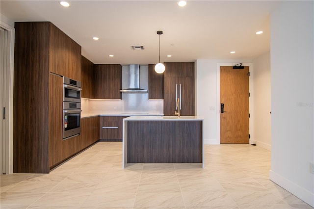 kitchen with light countertops, wall chimney exhaust hood, modern cabinets, and pendant lighting