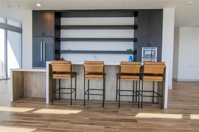 bar with paneled fridge, wood finish floors, and baseboards