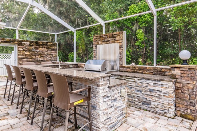 view of patio / terrace with area for grilling, exterior bar, and a lanai